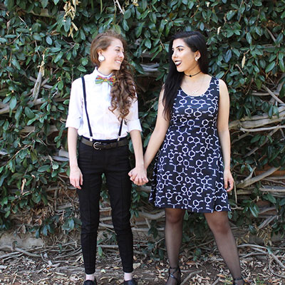 UCR couple Sonia & Mariah stand holding hands in front of Watkins