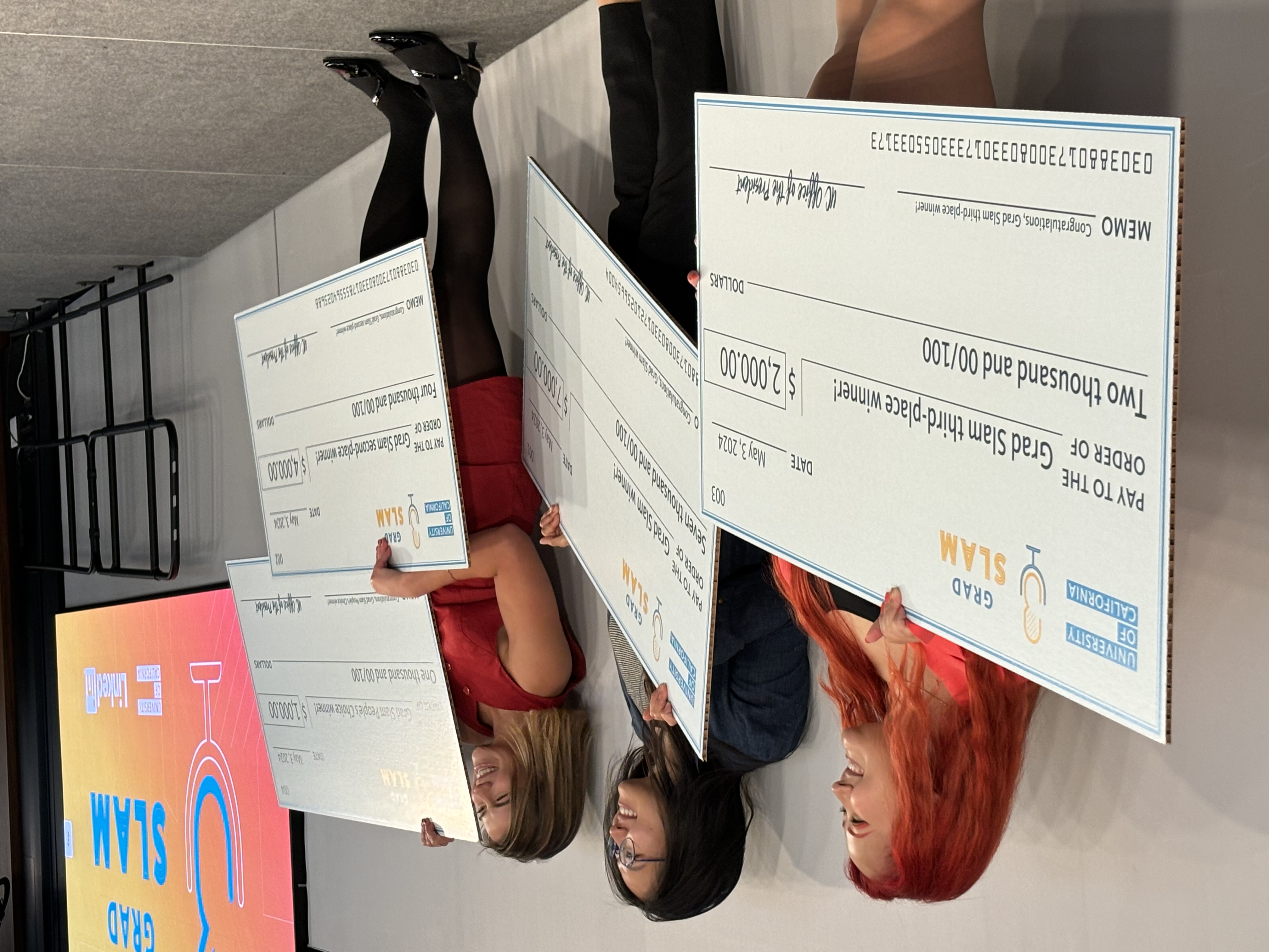 UC Grad Slam winners holding giant award checks