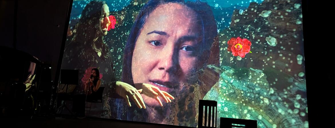 Photo of video projection of actress Rinska Carrasco in a performance of "I Hear America Singing."