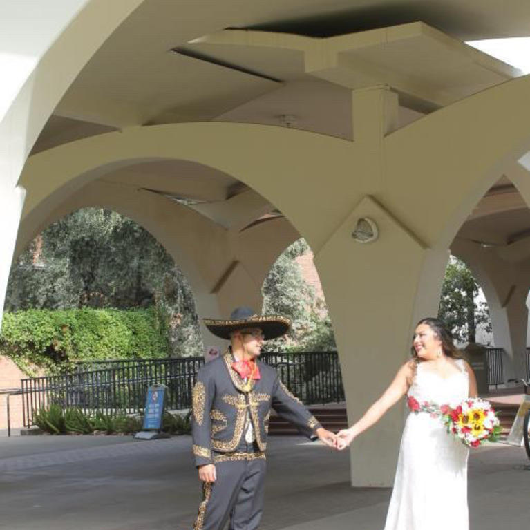 Couple poses on their wedding day under the Rivera arches at UC Riverside 