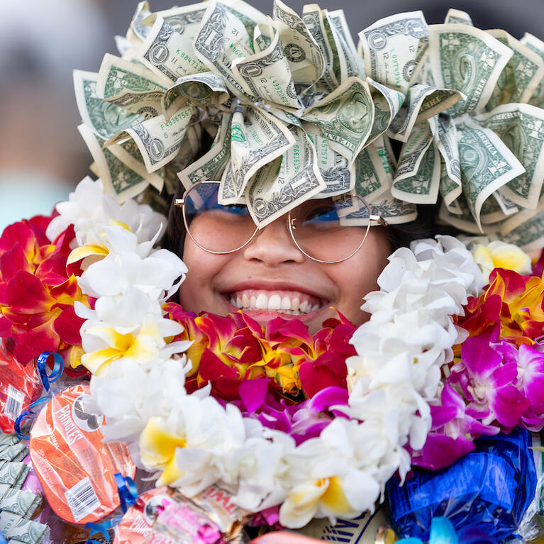 Graduate covered in floral leis and money crown