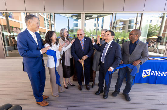UCR officials cutting a blue ribbon at an outdoor building dedication.